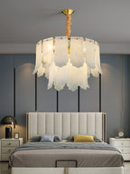 The Clérachic Hue Alabaster Chandelier centred over an upholstered bed, its domed brass canopy fixed to a blue-grey bedroom ceiling.