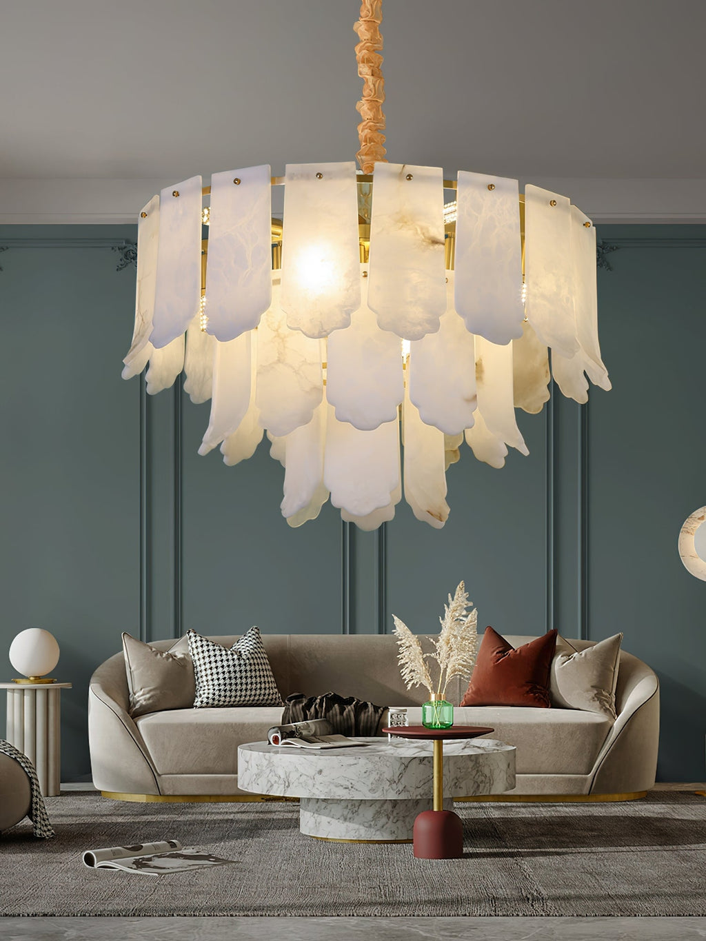 Close view of the Clérachic Hue Alabaster Chandelier lighting a curved sofa and marble coffee table against a deep teal panelled wall.