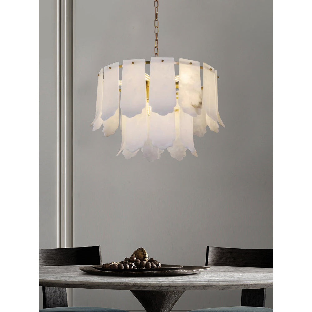 The nine-light Clérachic Hue Alabaster Chandelier on a brass chain above a dining table dressed with a dark stone bowl.