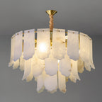 The Clérachic Hue Alabaster Chandelier lit on a grey studio ground, the heads reading as soft flares behind the stone plates.