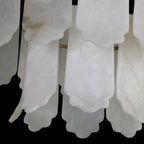 Detail of the scalloped hems on the Clérachic Hue Alabaster Chandelier, one plate carrying a warm amber seam through white stone.