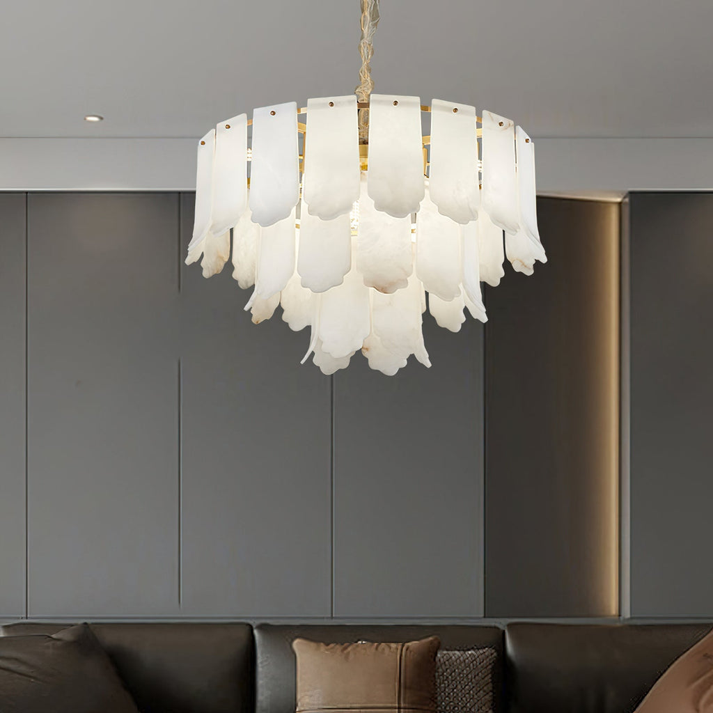 The Clérachic Hue Alabaster Chandelier hung against grey panelled joinery, its stone tiers lit above a dark sofa.