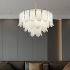 The Clérachic Hue Alabaster Chandelier hung against grey panelled joinery, its stone tiers lit above a dark sofa.
