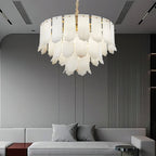 The Clérachic Hue Alabaster Chandelier lit in a contemporary lounge, framed by a ribbed feature wall and a low grey sofa.