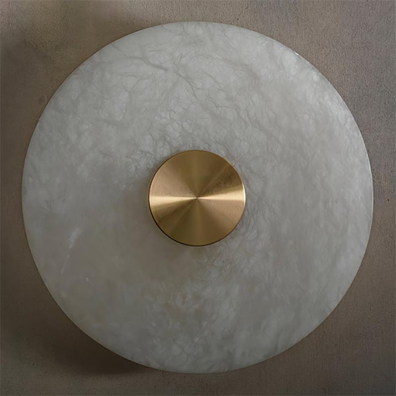 The Clérachic sconce shown close up, natural alabaster veining running across the full width of the round stone shade.