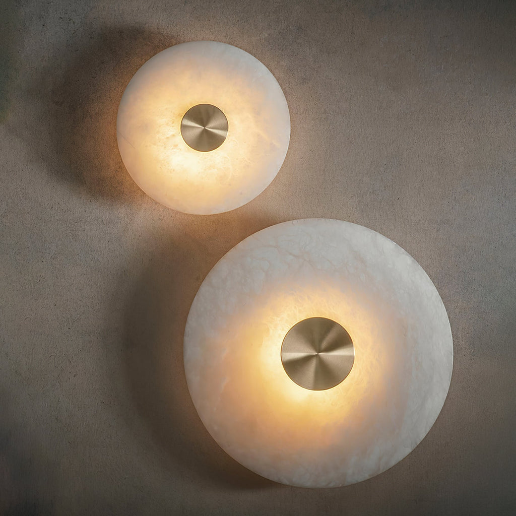 The Clérachic small and large discs lit together, each throwing a soft halo across the plaster surface.