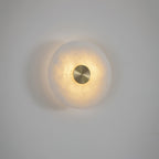 The Clérachic wall lights mounted so the two discs overlap, lit warm against a pale, softly shadowed wall.