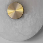 Extreme close-up of the Clérachic brass centre cap, seated against translucent alabaster full of cloud-like veining.