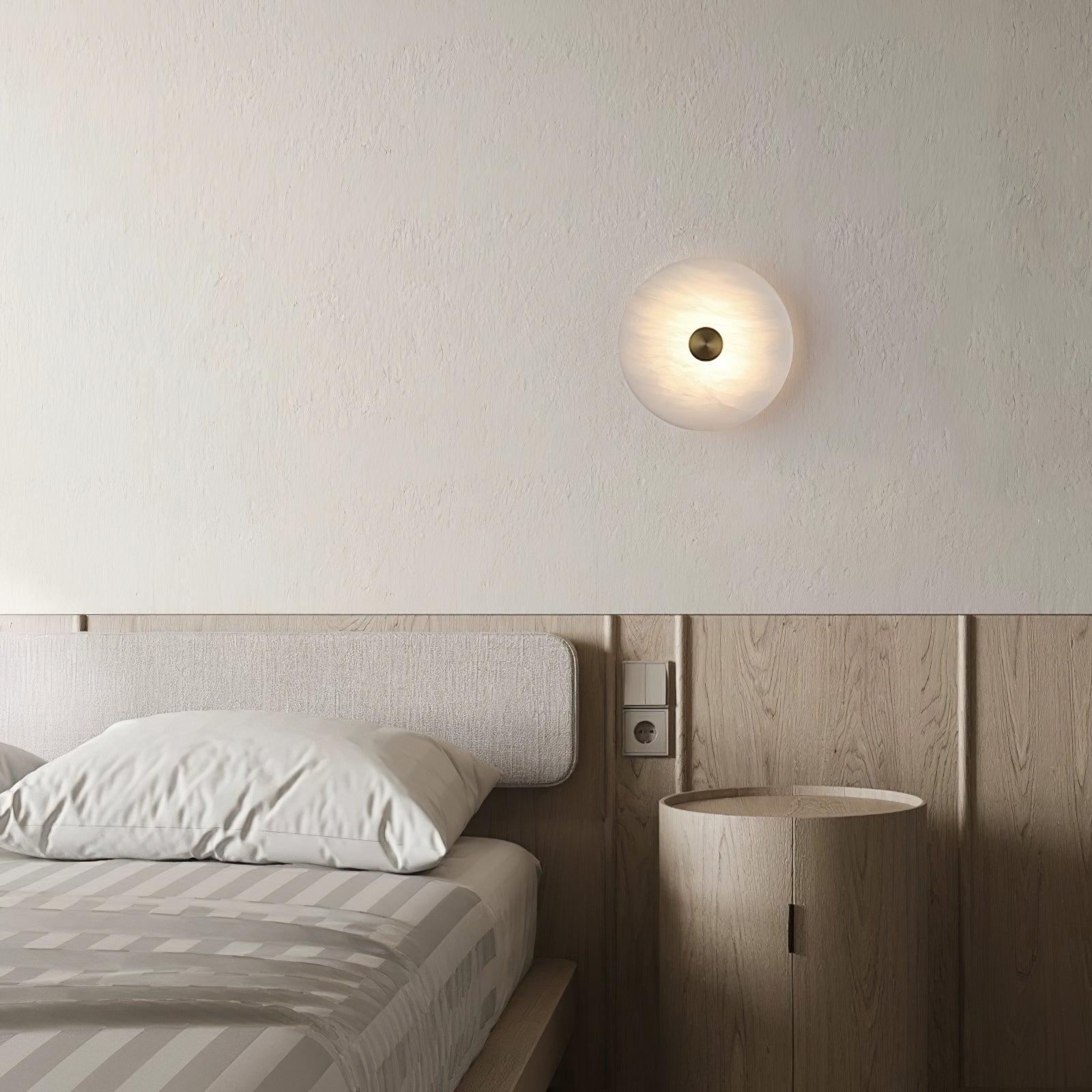 The Clérachic sconce lit above an oak-panelled headboard, casting a soft circle of light in a bedroom.