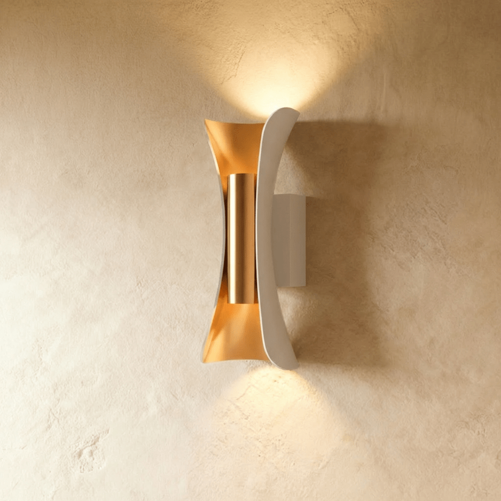 Clérachic white curved wall lamp with a brushed gold inner reflector, casting light up and down a limewash wall.