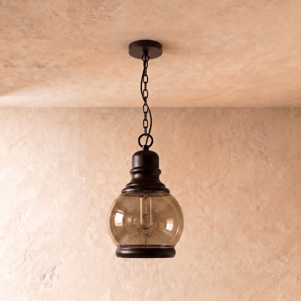 Clérachic round amber-tinted glass globe pendant on a black chain, switched off so the filament bulb shows inside.