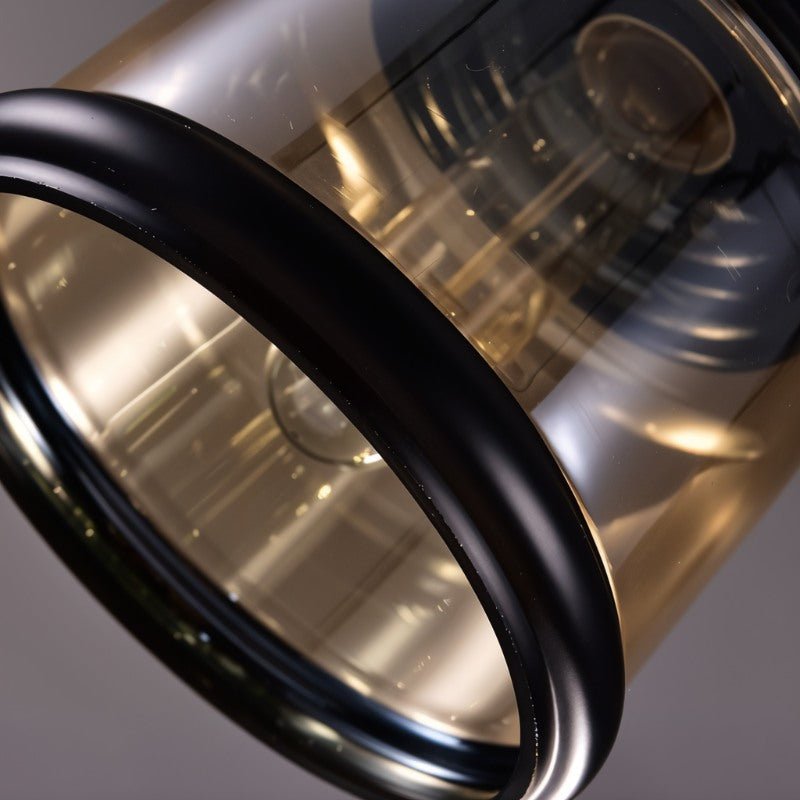 Close view of the black rim of a Clérachic cylindrical amber glass pendant, looking up into the shade and bulb.
