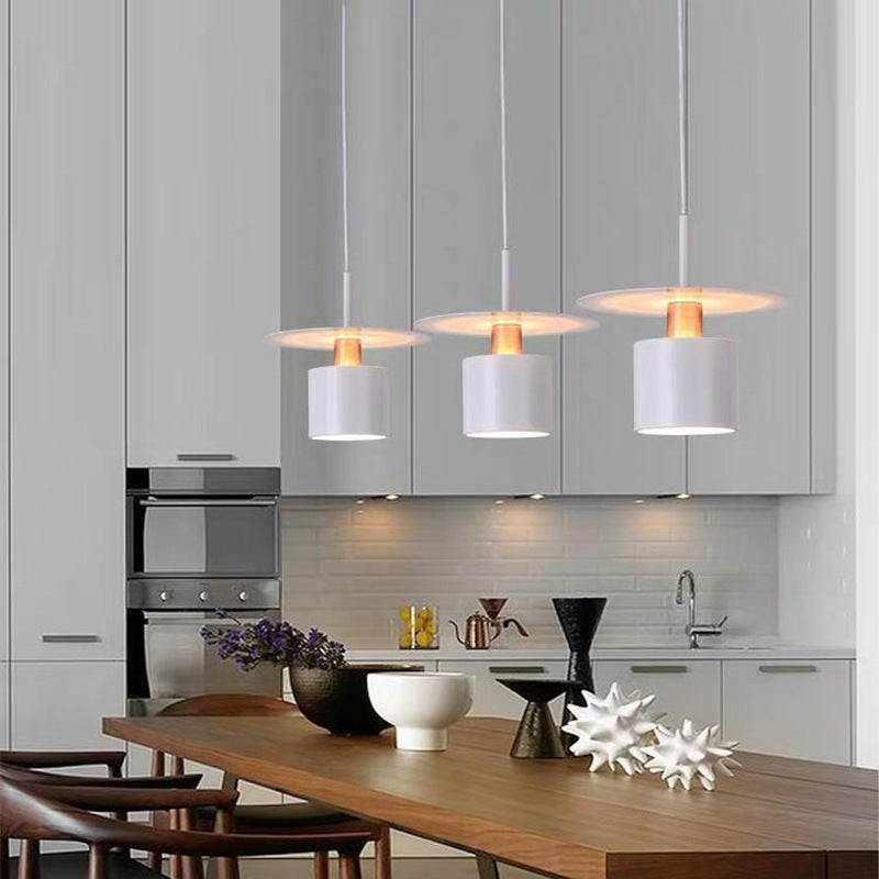Clérachic trio of white saucer pendants with copper necks over a wooden dining table in a kitchen.