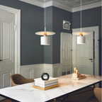 Clérachic two white copper-neck pendants over a marble table in a room with dark walls and white doors.
