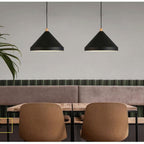 Two Clérachic black 1-light cone pendants hang over a pale wood café table and brown chairs.