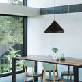 A Clérachic black 1-light cone pendant hangs over a wood dining table ringed by mint-green chairs.