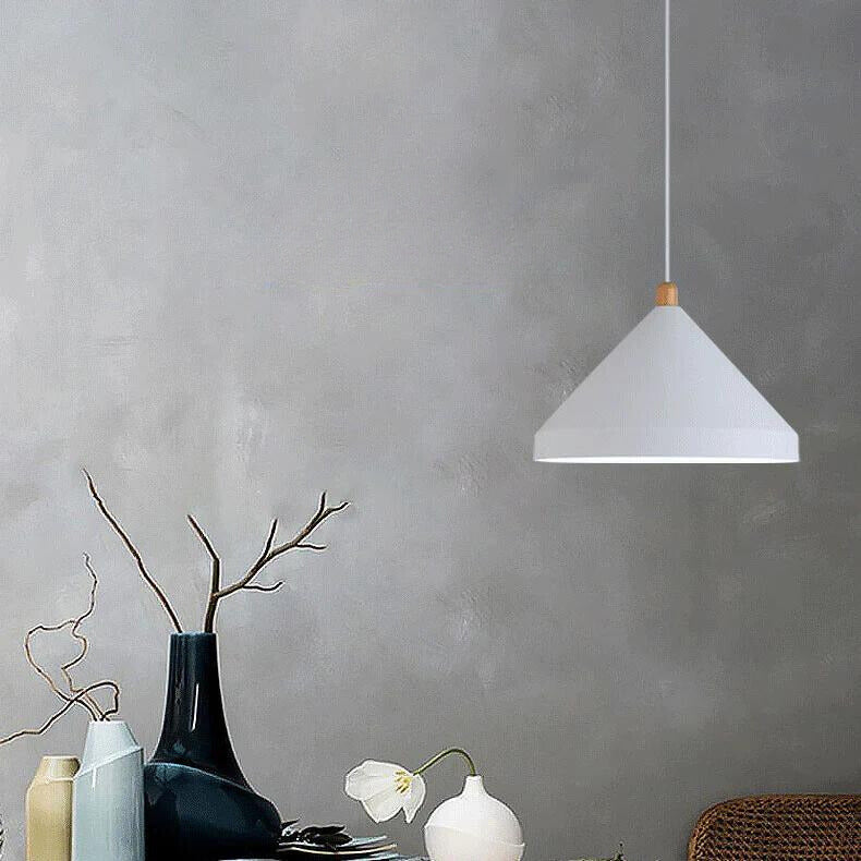Clérachic white 1-light cone pendant with a wood neck, lit above blue and yellow vases on a grey wall.