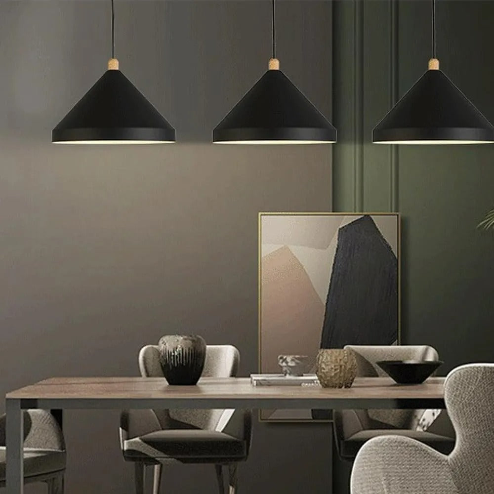 Three Clérachic black 1-light cone pendants light a dining table set with dark vases and a black bowl.
