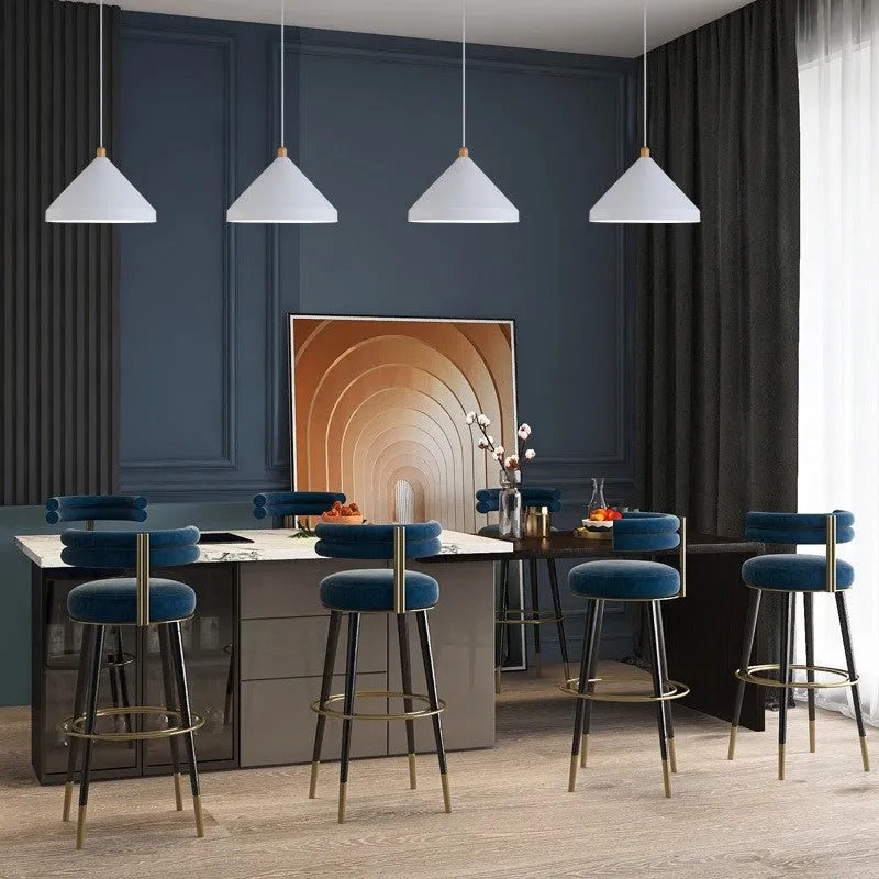 Four Clérachic white 1-light cone pendants hang in a row over a kitchen island with blue velvet stools.