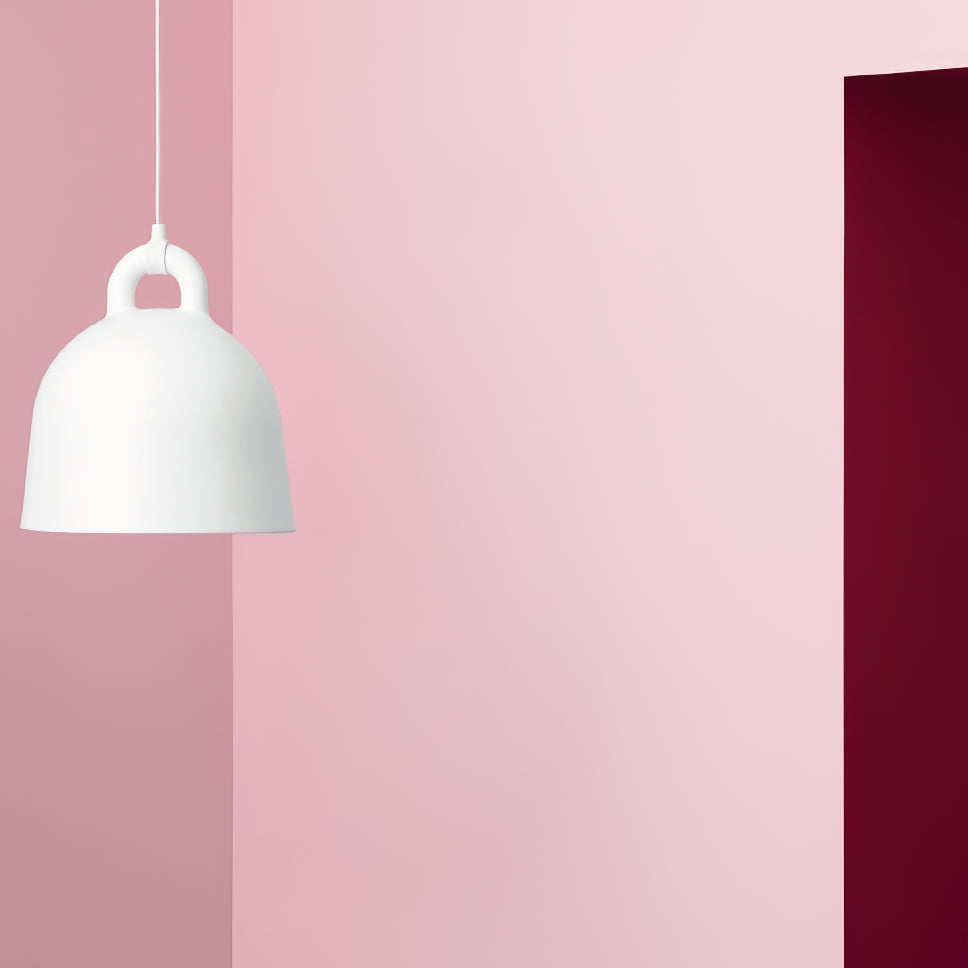 A white Clérachic bell pendant on a pink wall, cropped at the edge of the frame beside a deep red door.