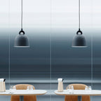 Two grey Clérachic bell pendants hang over cafe tables with tan chairs, against a blue-grey gradient wall.