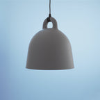 Close view of a large grey Clérachic bell pendant with matte finish, hanging against a pale blue backdrop.