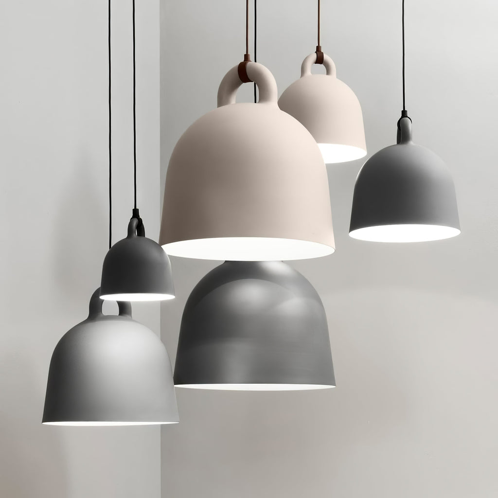 A group of grey and sand-coloured Clérachic bell pendants hangs at staggered heights in a pale grey room.