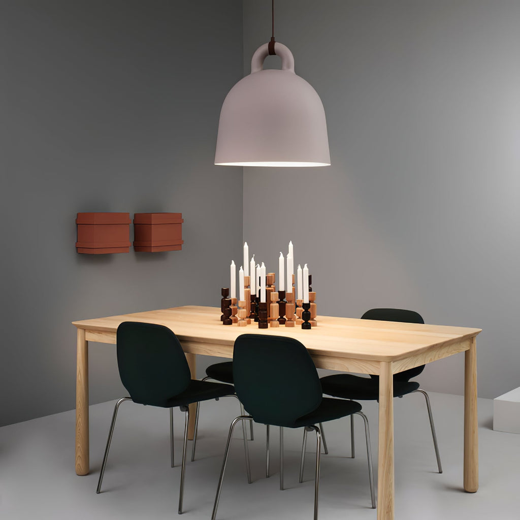A large taupe-pink Clérachic bell pendant hangs over a wooden table with black chairs and a cluster of candlesticks.