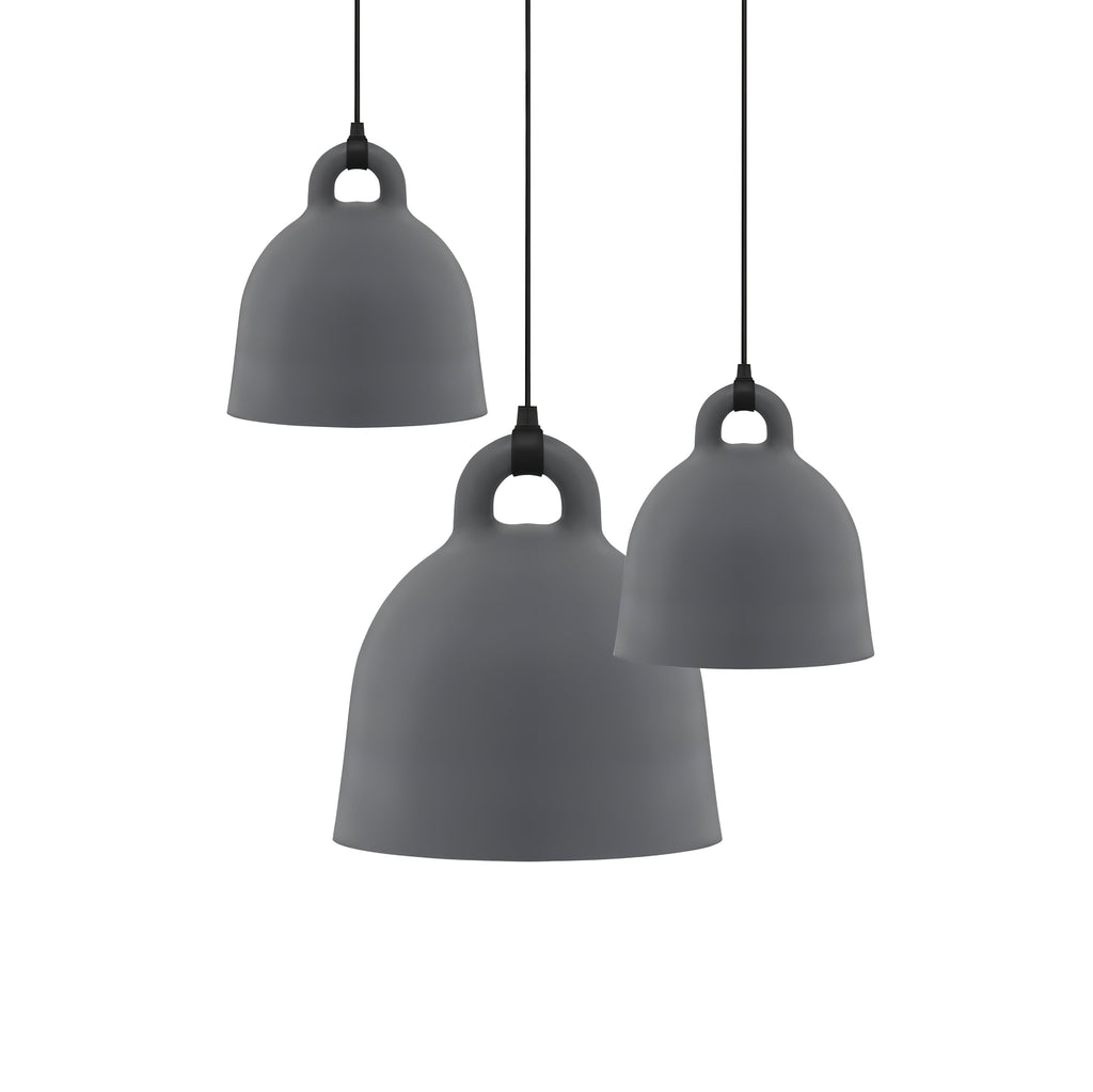 Three grey Clérachic bell pendants in different sizes hang at staggered heights on a plain white backdrop.