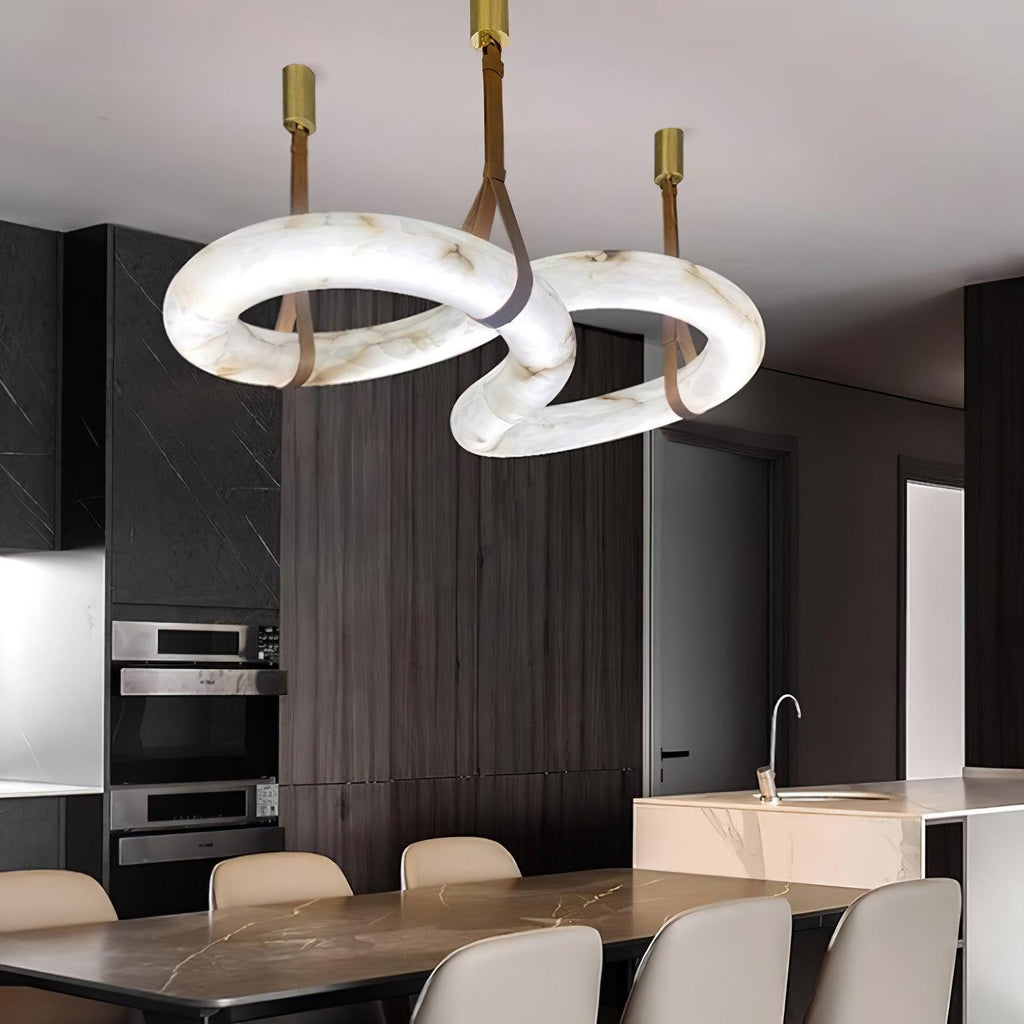 Clérachic Infinity pendant lit above a dining table in a dark timber kitchen with a stone island.