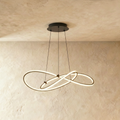Clérachic pendant of interlaced LED loops in black on three thin cables, glowing against a limewashed wall and ceiling.