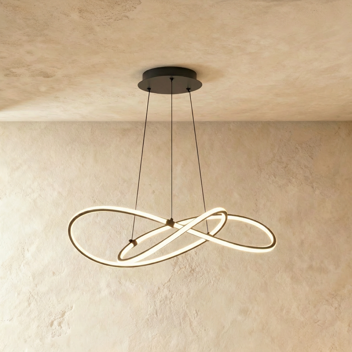 Clérachic pendant of interlaced LED loops in black on three thin cables, glowing against a limewashed wall and ceiling.