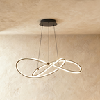 Clérachic mid-length black looped LED pendant lit warm, hanging from a round black canopy against a plaster wall.