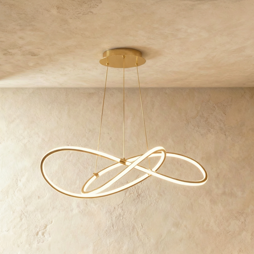 Clérachic mid-length brass looped LED pendant, glowing softly below a round brass canopy on a limewashed wall.