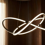 Close detail of the Clérachic black pendant, where its glowing LED loops cross and meet at the dark metal clamps.