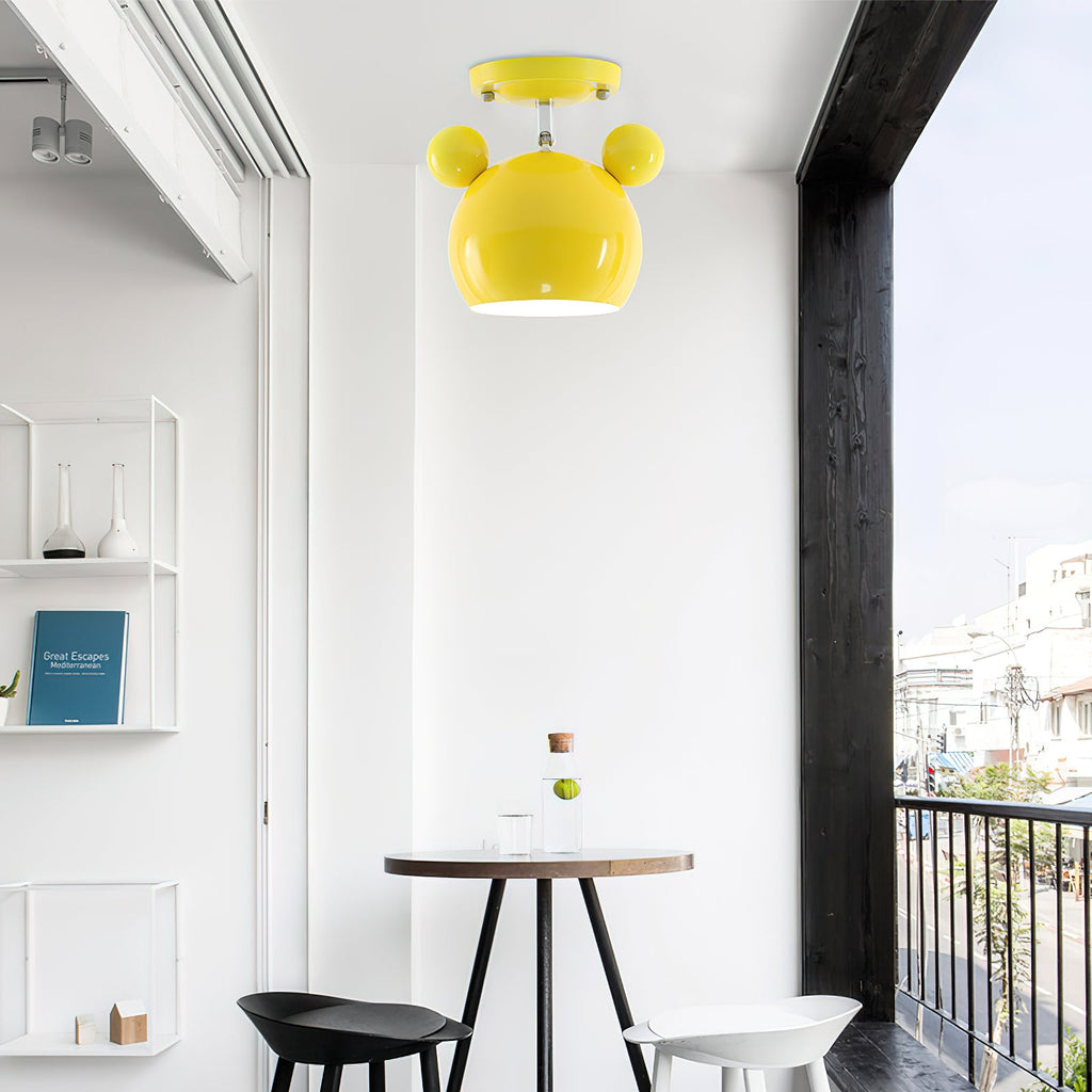 Yellow Clérachic ceiling lamp above a small round table and black chairs, beside a balcony door and open shelving.