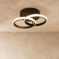 Clérachic black iron ceiling light with two overlapping glowing acrylic rings on a round canopy, flush on limewash plaster.