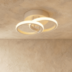 Clérachic white iron ceiling light with two overlapping glowing acrylic rings on a round canopy, flush on limewash plaster.