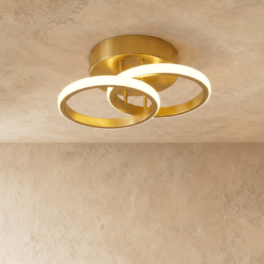 Clérachic brushed gold iron ceiling light with two overlapping glowing acrylic rings on a round canopy, on limewash plaster.