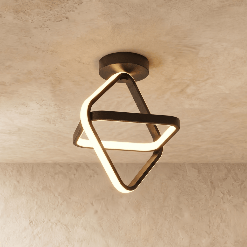 Clérachic black iron ceiling light of two interlocked tilted squares with a glowing acrylic edge, on a limewash ceiling.