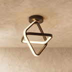 Clérachic black iron ceiling light of two interlocked tilted squares with a glowing acrylic edge, on a limewash ceiling.