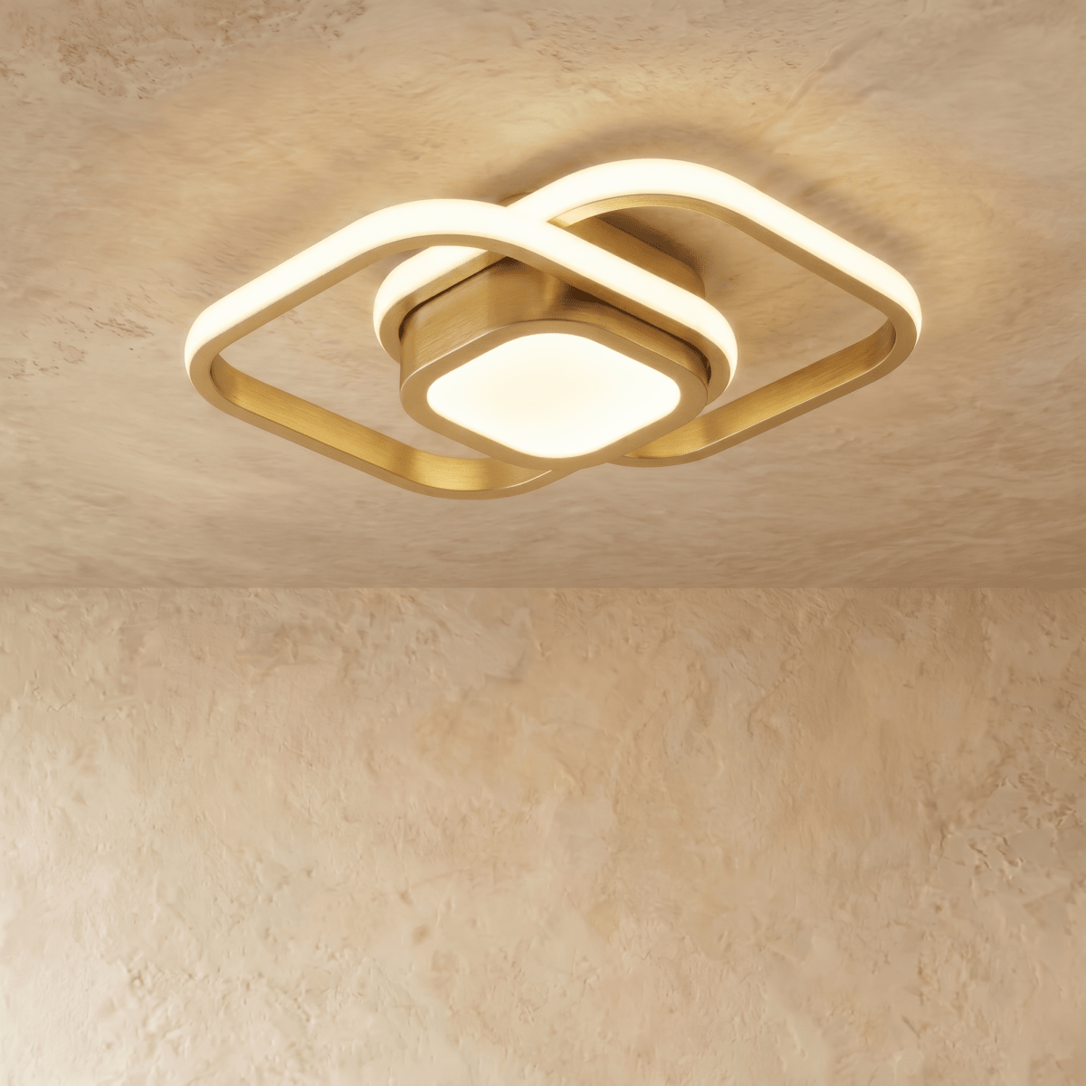 Clérachic brushed gold ceiling light with two overlapping rounded-square acrylic loops and a glowing square centre, on plaster.