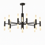 Clérachic black stick chandelier lit, its frosted tubes glowing a soft warm white against a plain white backdrop.