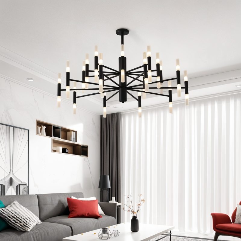 Clérachic black two-tier chandelier lit above a grey sofa and red cushions in a bright, white living room.
