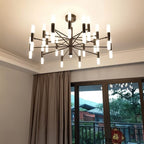 Clérachic black chandelier lit from a cream ceiling, its frosted tubes glowing beside a taupe curtain and balcony door.