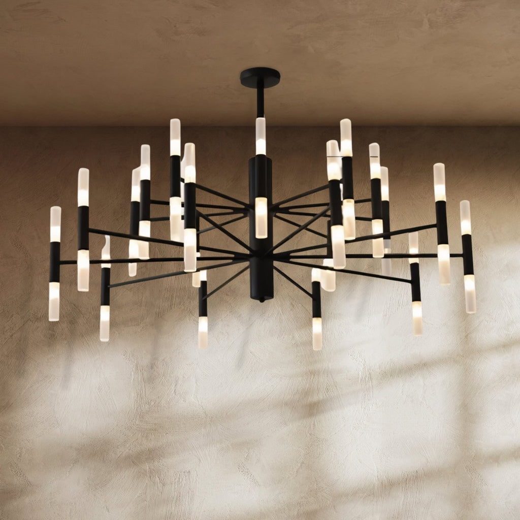 Clérachic black multi-tier chandelier lit against a textured plaster wall, with soft window shadows across it.