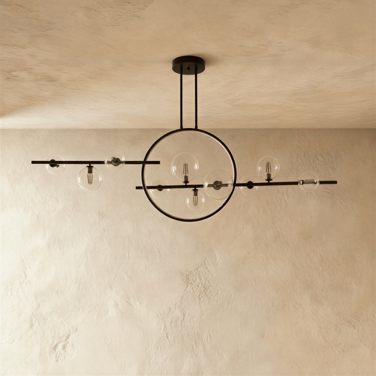 This angle of the Clérachic matte black iron chandelier shows the ring and bar globes catching light on plaster walls.