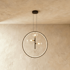 A Clérachic ring pendant stacks three glass globe bulbs vertically on a black rod inside its illuminated circle.