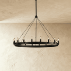 Clérachic matte black ring chandelier with candle-style bulbs around a flat iron band, lit against pale plaster.