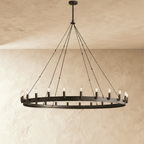 Clérachic large matte black ring chandelier with candle-style bulbs and long rods, hung against pale plaster.
